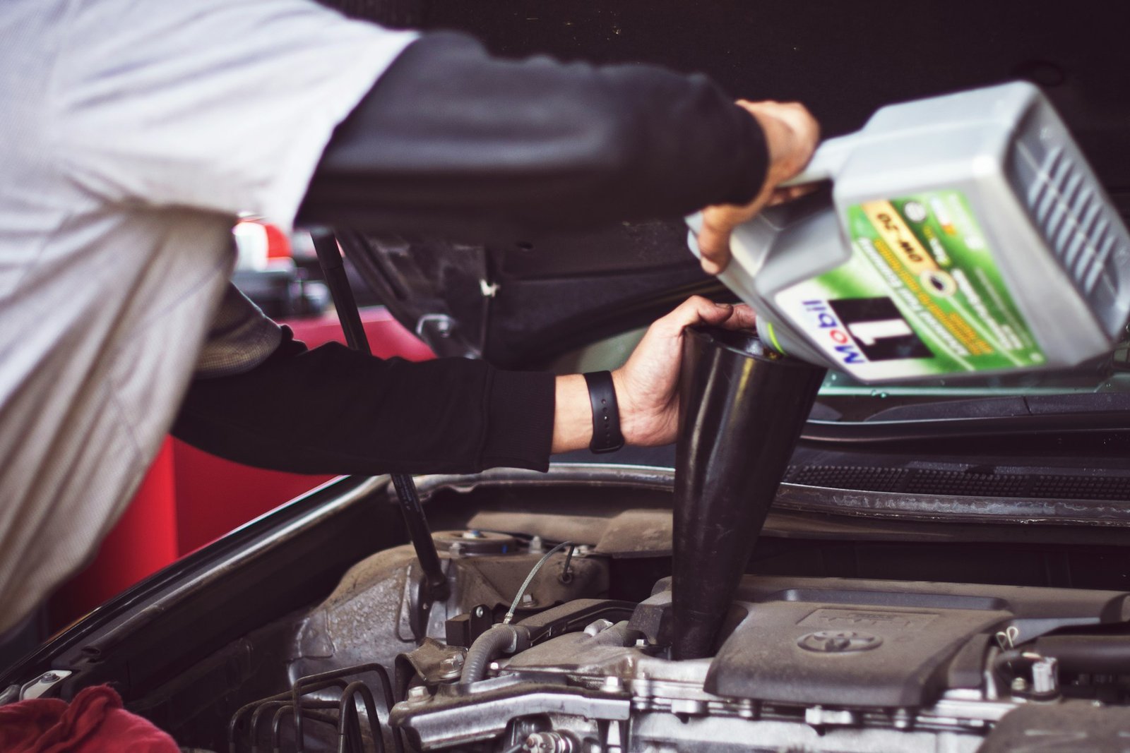 Man refilling motor oil on car engine bay